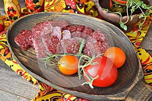 Dry salami sausage sliced Ã¢â¬â¹Ã¢â¬â¹on a wooden board and covered with spices, tomatoes. Russian cuisine